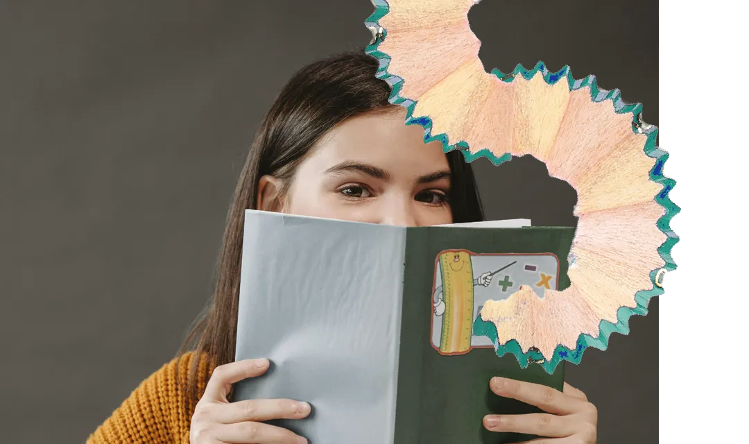 Eine junge Frau hält ein Buch vor ihr Gesicht und schaut darüber hinweg, verziert mit einer großen Bleistiftspäne und einer kleinen Zeichnung auf dem Buch.
