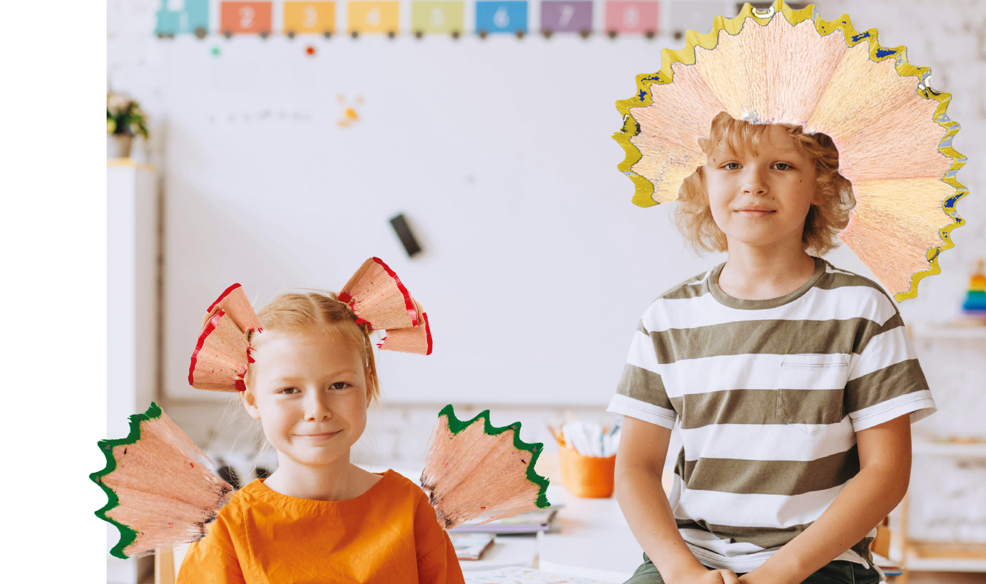 Zwei Kinder sitzen im Klassenzimmer und lächeln in die Kamera, dekoriert mit bunten Bleistiftspänen wie Flügeln und Kopfschmuck.